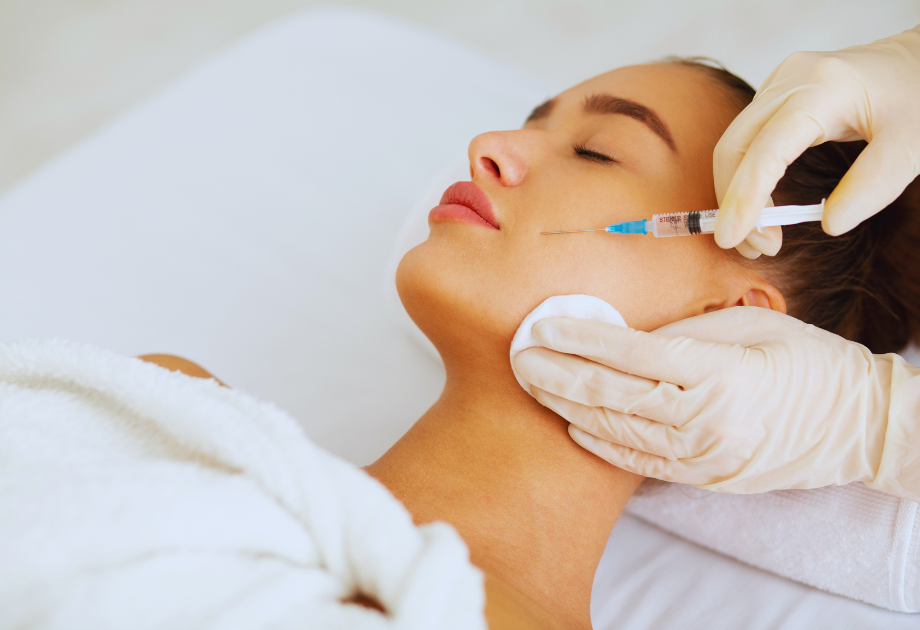 gloved hands hold a hypodermic needle to a woman's face